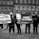 A group of people outside holding signs supporting Julian Assange, including one that says "Free Assange, no U.S. extradition"