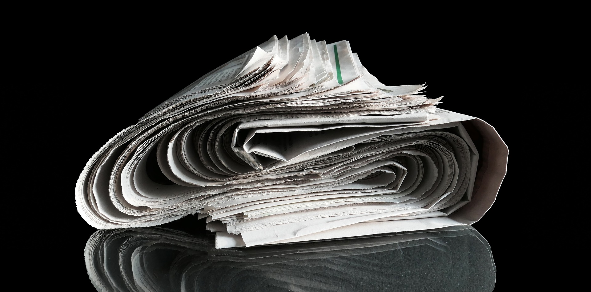 Newspaper rolled in S-curve on black background